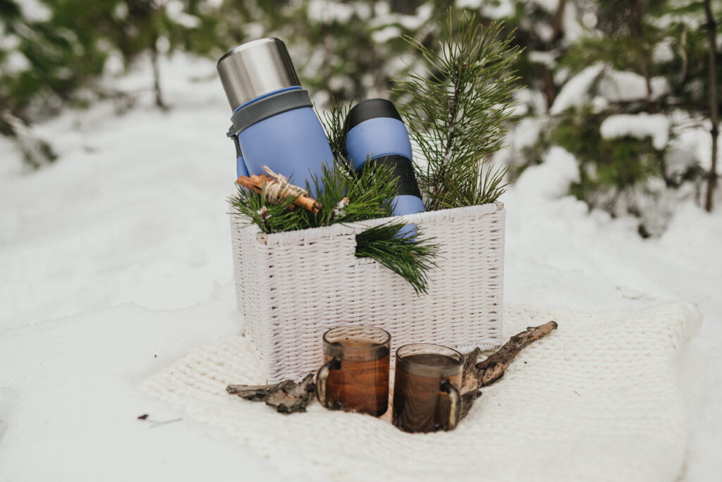 thermocup-thermos-with-cup-tea-pine-branches-lying-basket